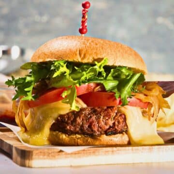 Bison burger with toothpick on cutting board.