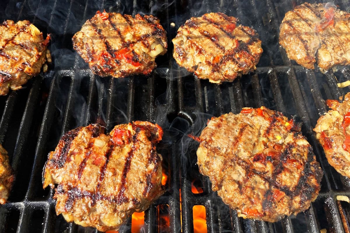 Bison burger patties cooking on the outdoor grill.