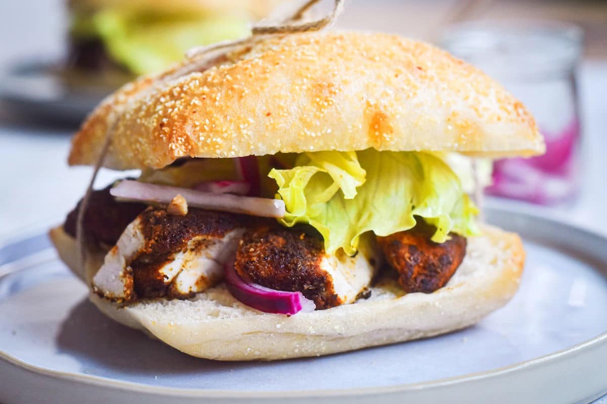 Blackened chicken sandwich with lettuce and red onion.