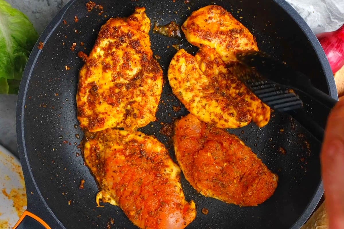 Blackened chicken breasts in pan.