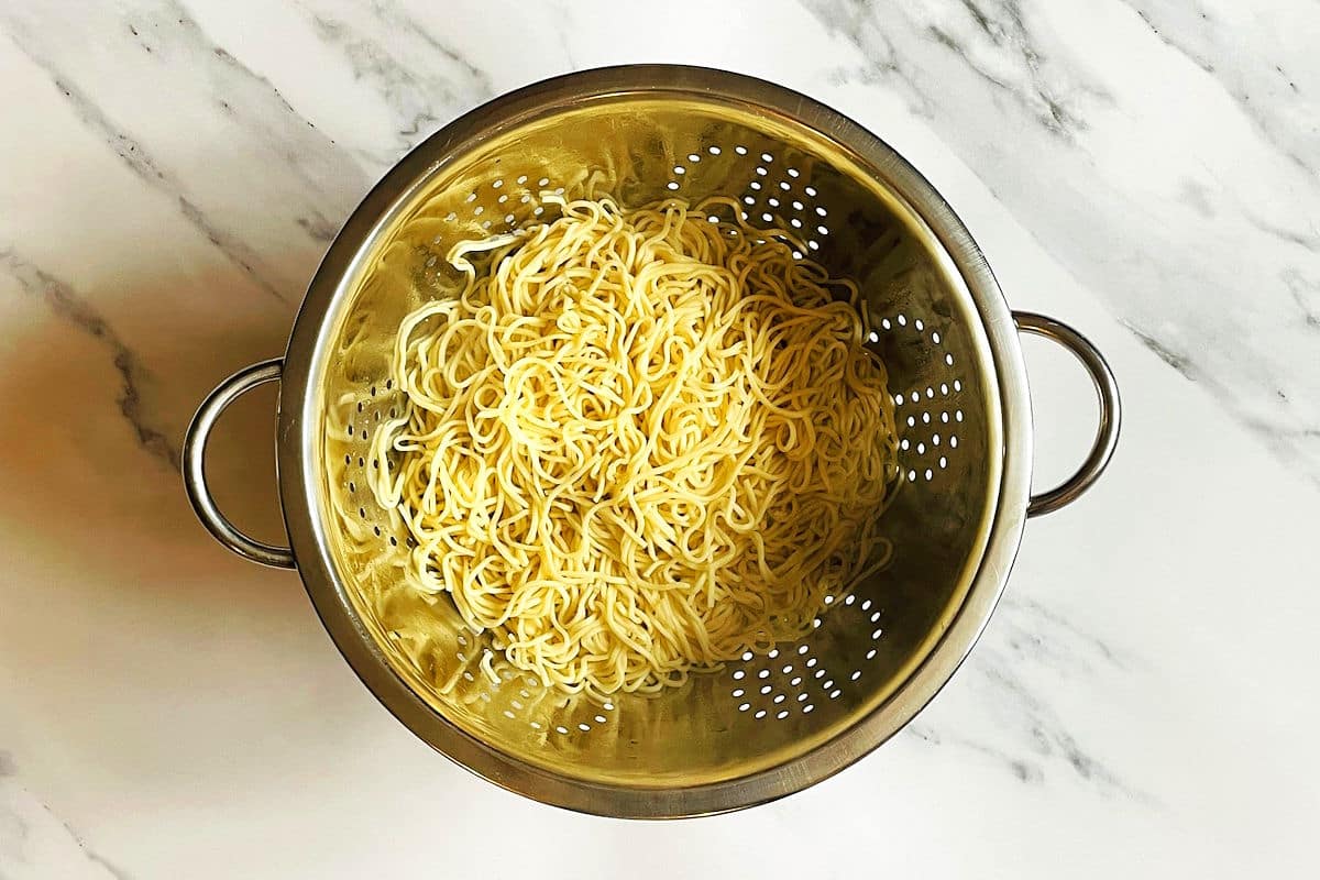 Cooked chow mein noodles in colander.