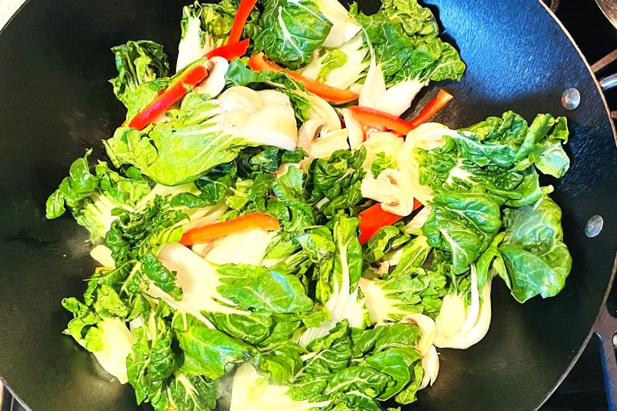 Bok choy, red peppers and mushrooms in wok.