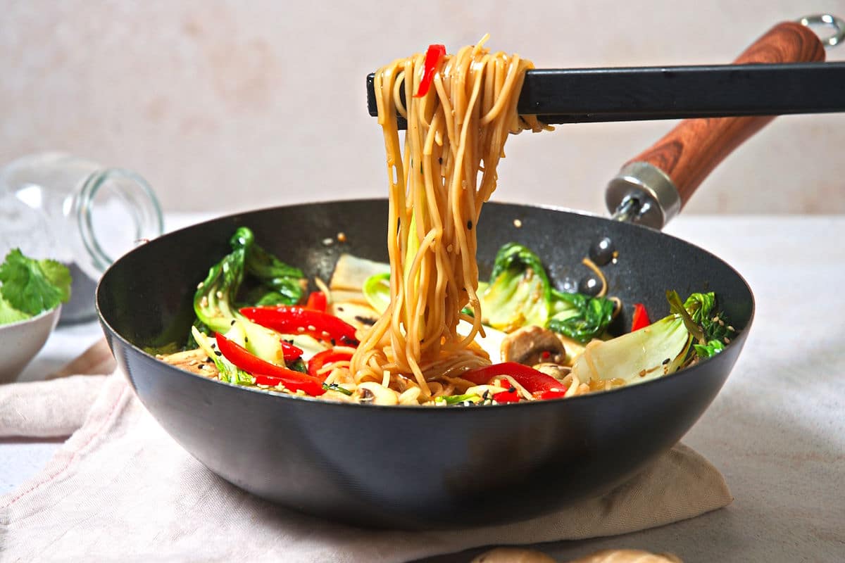 Bok choy stir fry in pan with chopsticks.