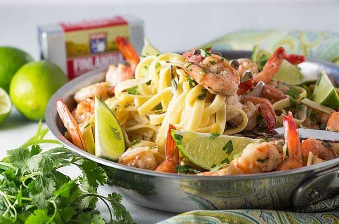 Fettuccine with shrimp and limes in pan.