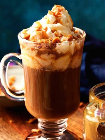 Caramel brûlée latte and sauce on blue background.