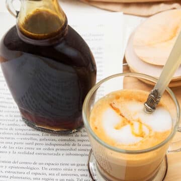 Caramel syrup in a jar and hot coffee in a mug.