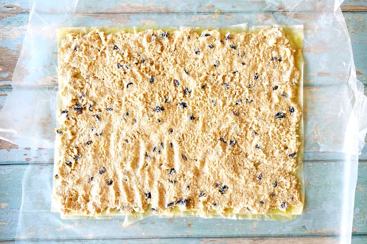 Cheese strudel filling spread out on buttered phyllo sheets.