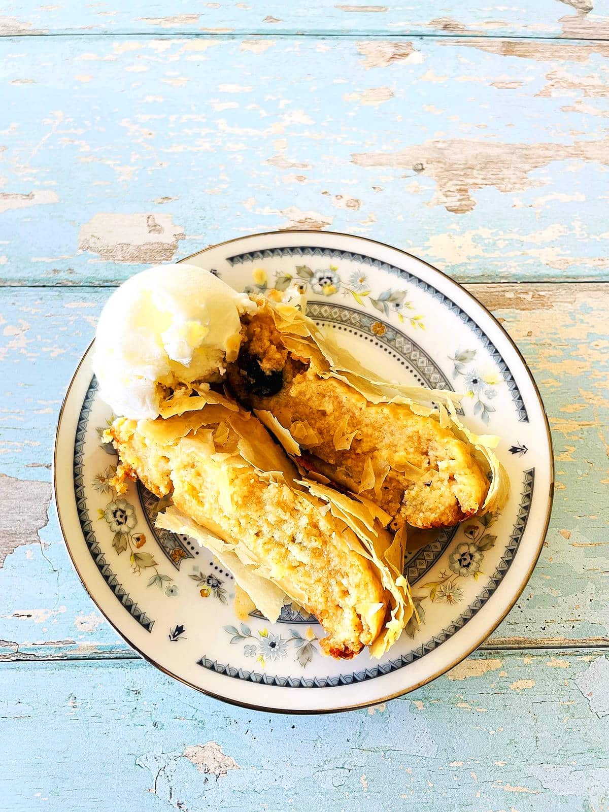 Slices of cheese strudel on a plate with a scoop of ice cream.