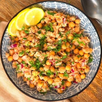 Chickpea and salmon salad in bowl with lemon slices.