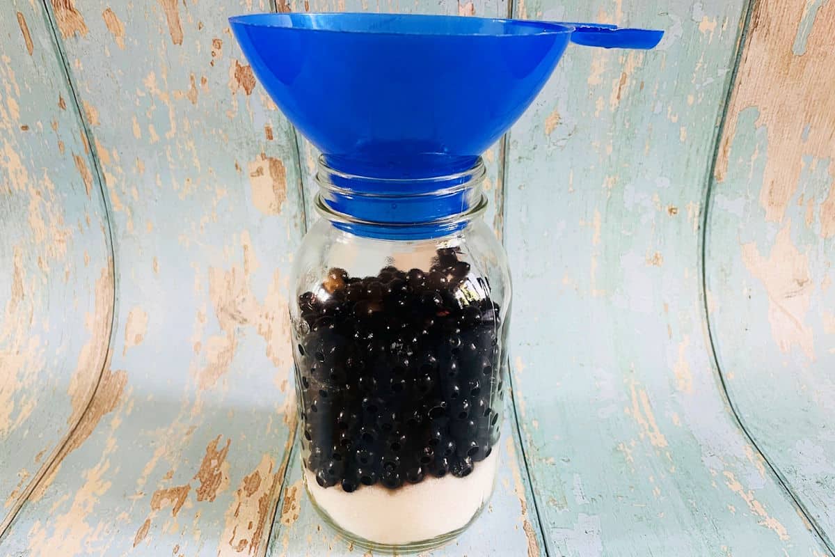 Chokecherries and sugar in jar.