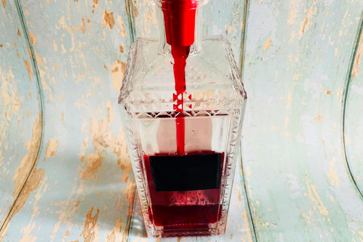 Chokecherry liqueur getting funneled into glass bottle.
