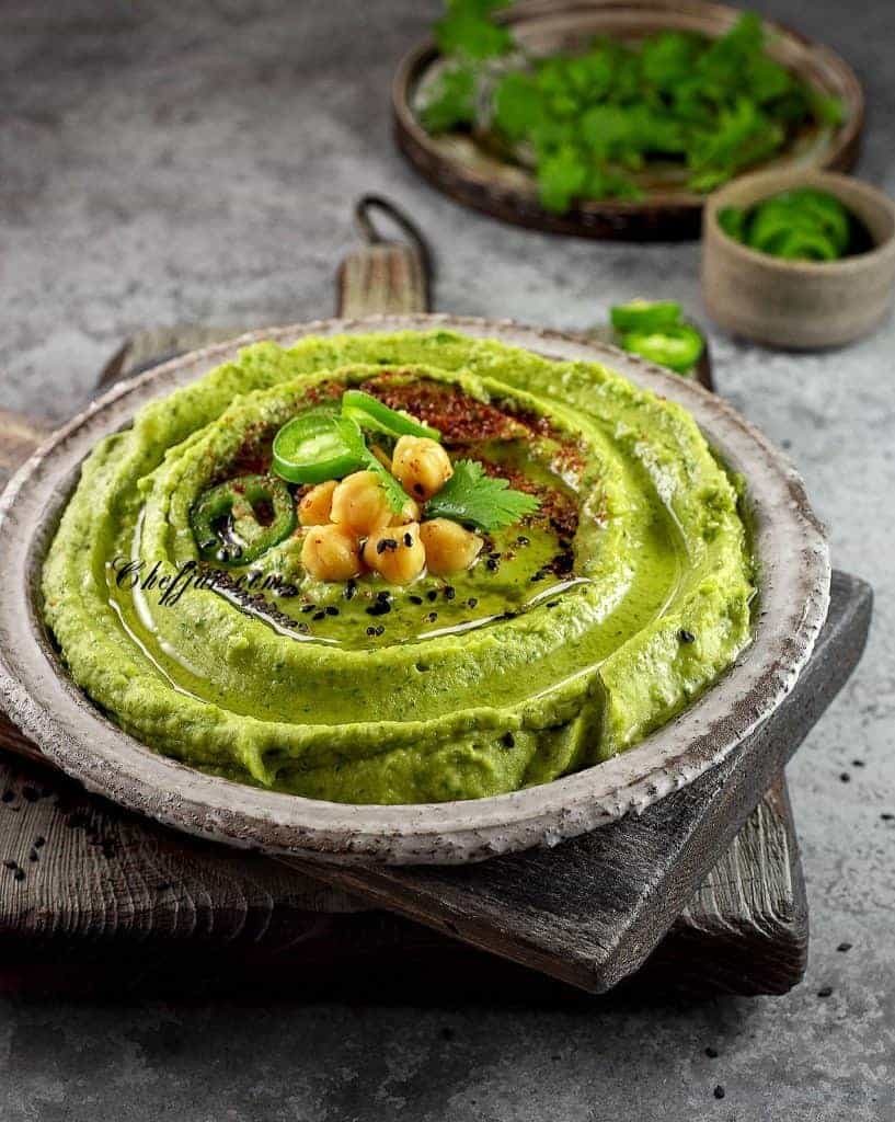 Cilantro hummus in grey bowl on grey background.