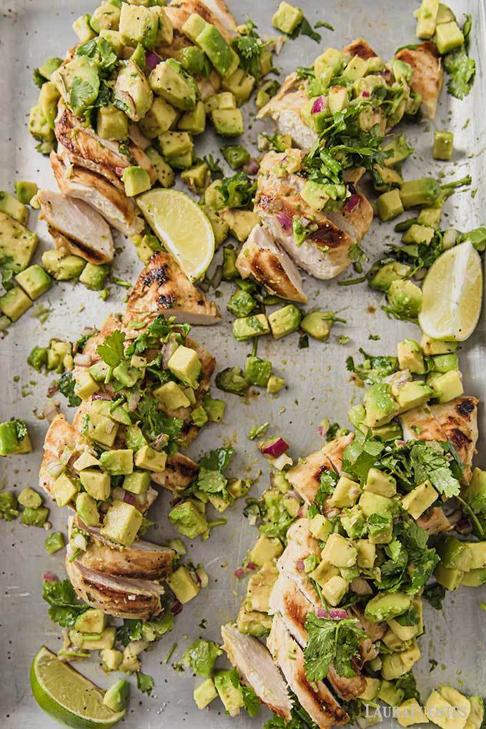 Sheet pan with chicken breast, cubed avocado, cilantro and lime wedges.