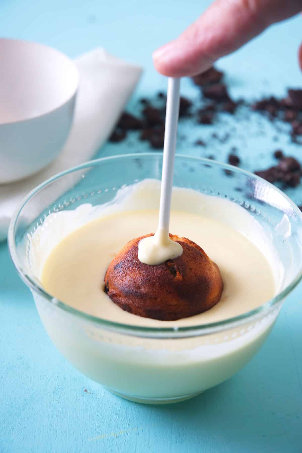 Cookies and cream cake pop dipped into bowl of white candy melts.