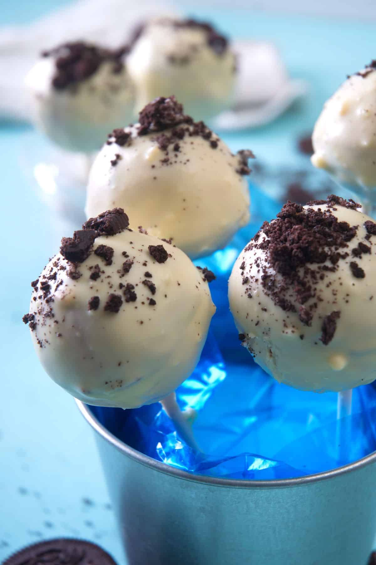 Cookies and cream cake pops in a decorative, blue, mini pail.