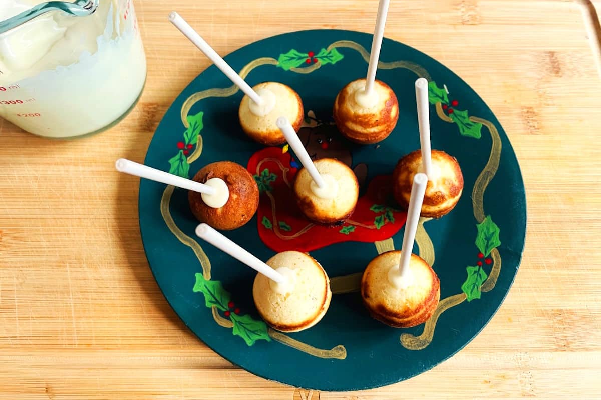 Cake balls with treat sticks on Christmas plate.