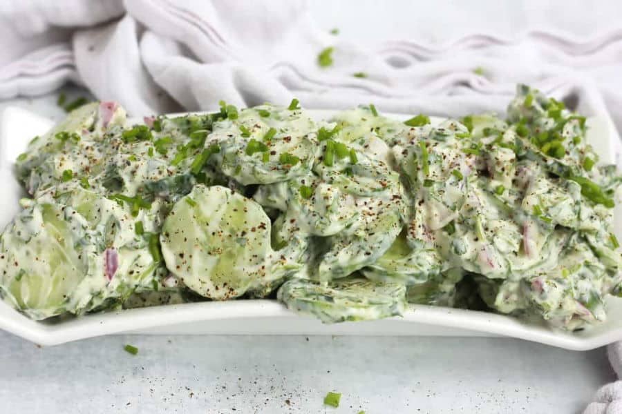 Cucumber salad on white dish, light background.