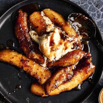 Bananas Foster on black plate with ice cream.