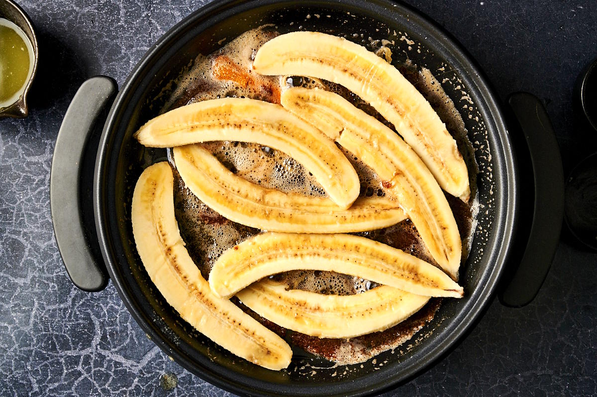 Sliced bananas in brown sugar sauce in skillet.