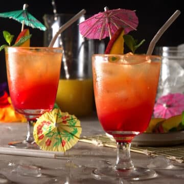 Hawaiian Mai Tais with umbrellas, straws and mango slices.