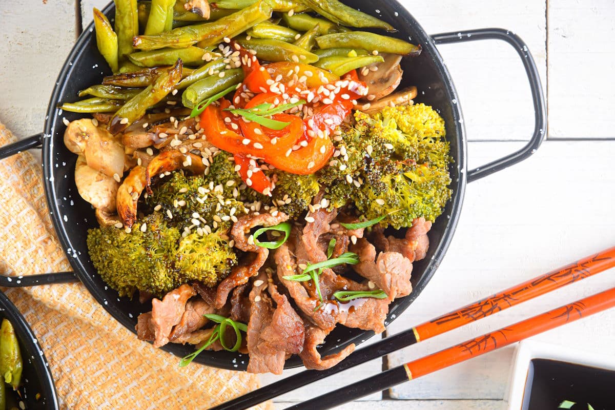 Beef and broccoli in bowl with chopsticks.