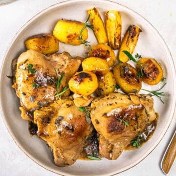 Greek lemon chicken thighs and baby potatoes on plate.