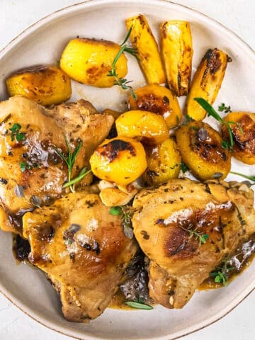 Greek lemon chicken thighs and baby potatoes on plate.
