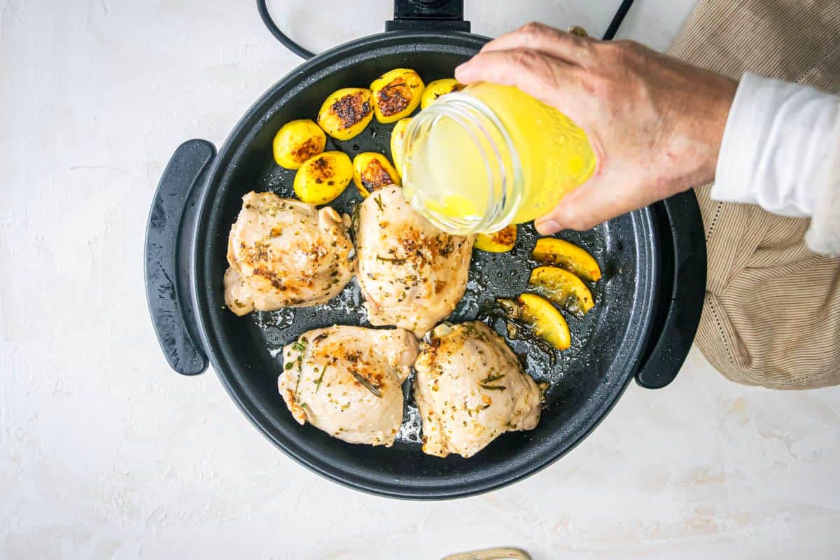 Greek chicken thighs, lemon wedges and baby yellow potatoes in electric skillet with broth.