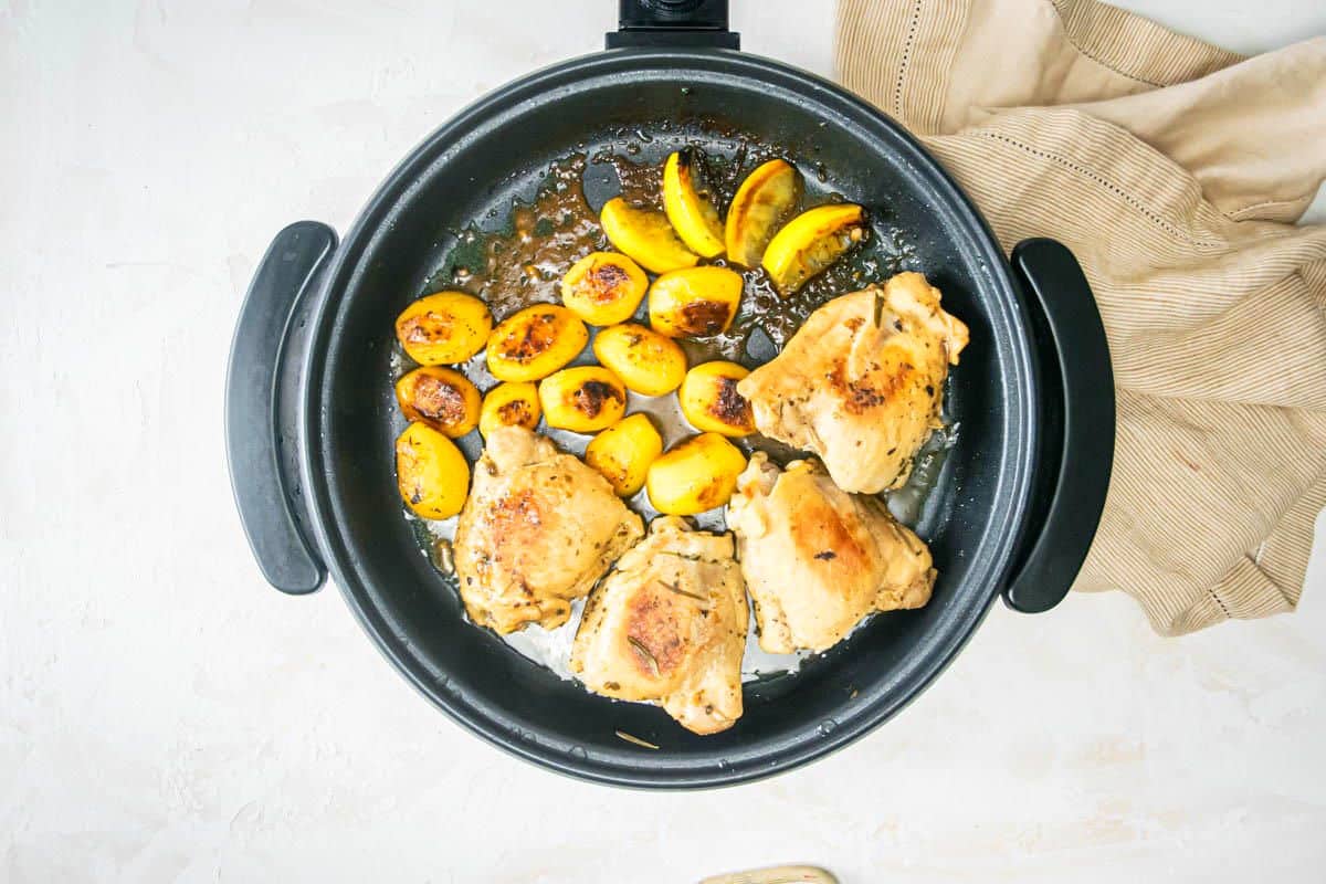 Cooked Greek lemon chicken thighs and potatoes in electric skillet.
