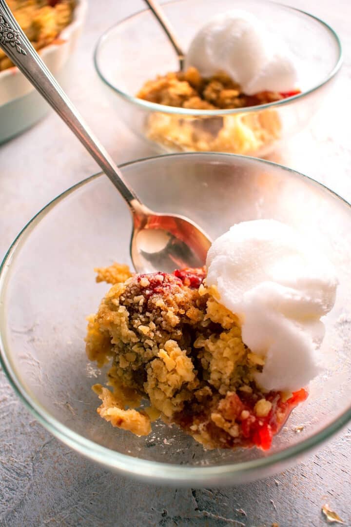 Strawberry crumble in bowl with vanilla ice cream.