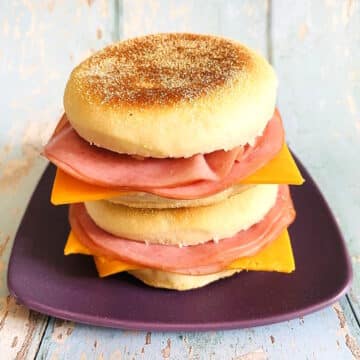 English muffin sandwiches stacked on purple plate.