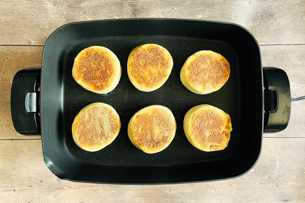 Golden brown English muffins in electric skillet.