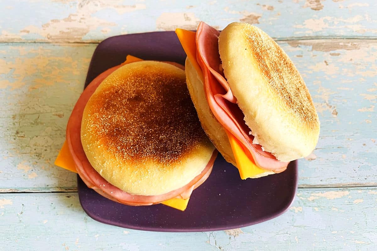 English muffin sandwiches with ham and cheese on plate.