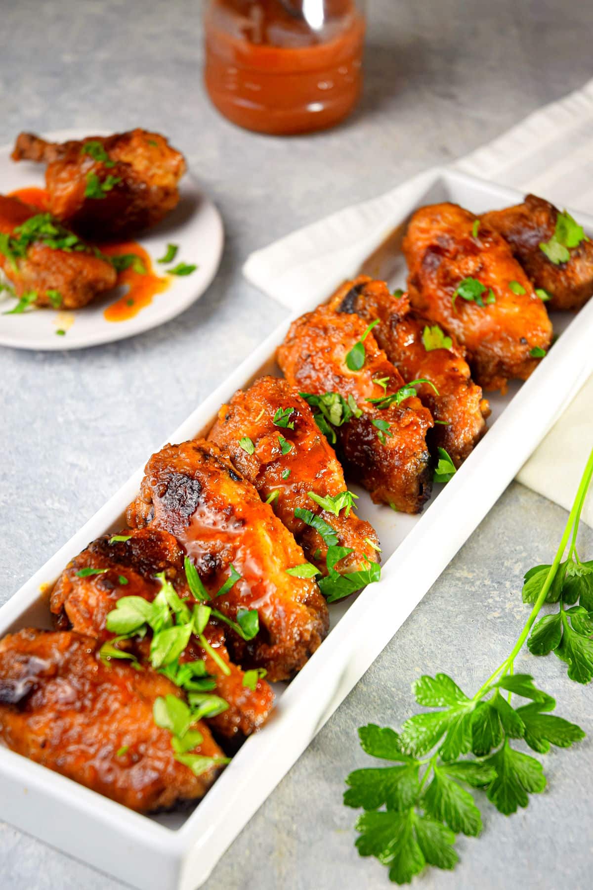 BBQ buffalo wings in dish with fresh parsley.