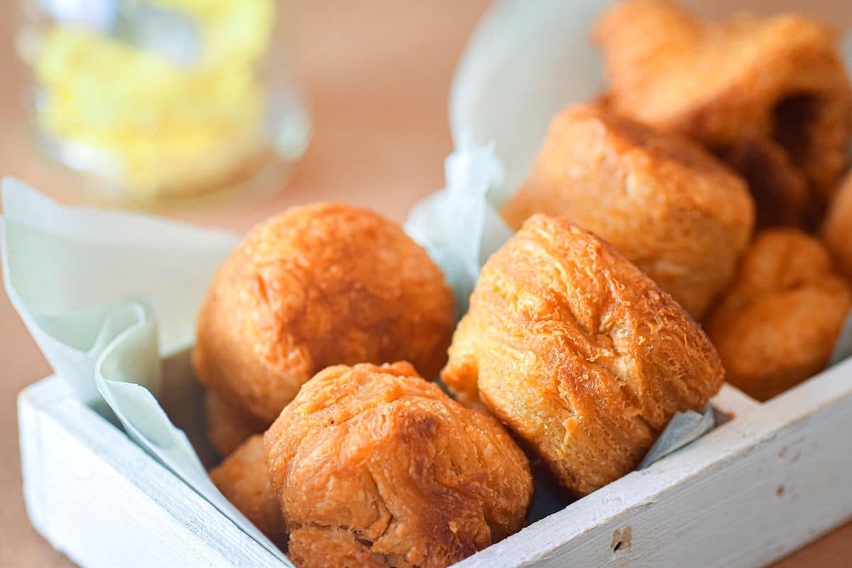 Golden biscuits in white wooden serving tray.