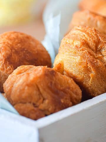 Golden biscuits in white wooden serving tray.