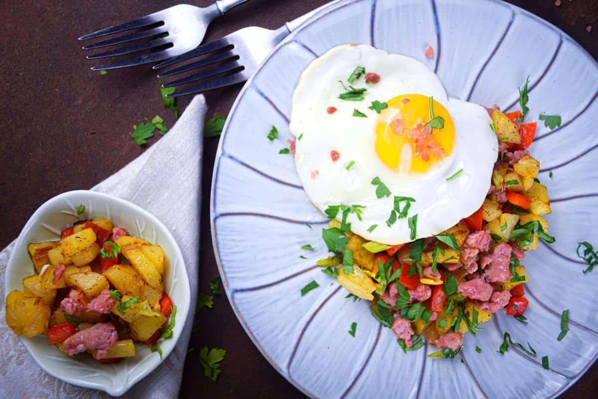 Skillet breakfast hash on plate with fresh parsley and forks on the side.