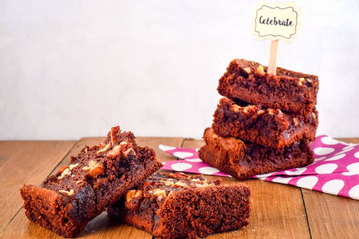 Electric skillet brownies sliced and stacked on wooden table.