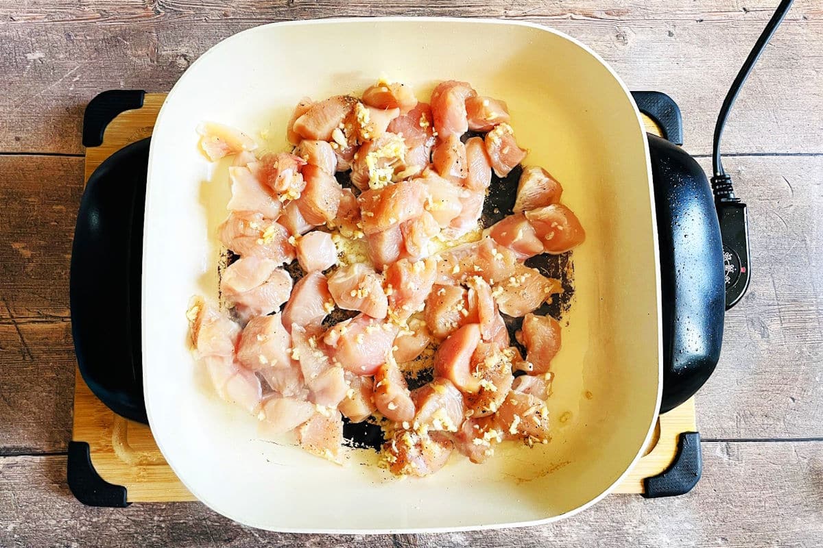 Chicken breast pieces cooking in electric skillet.