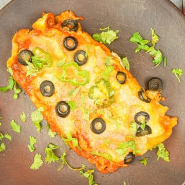 Electric skillet chicken enchiladas on brown plate.