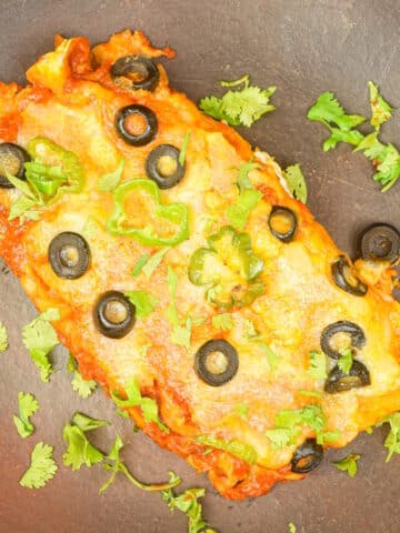 Electric skillet chicken enchiladas on brown plate.