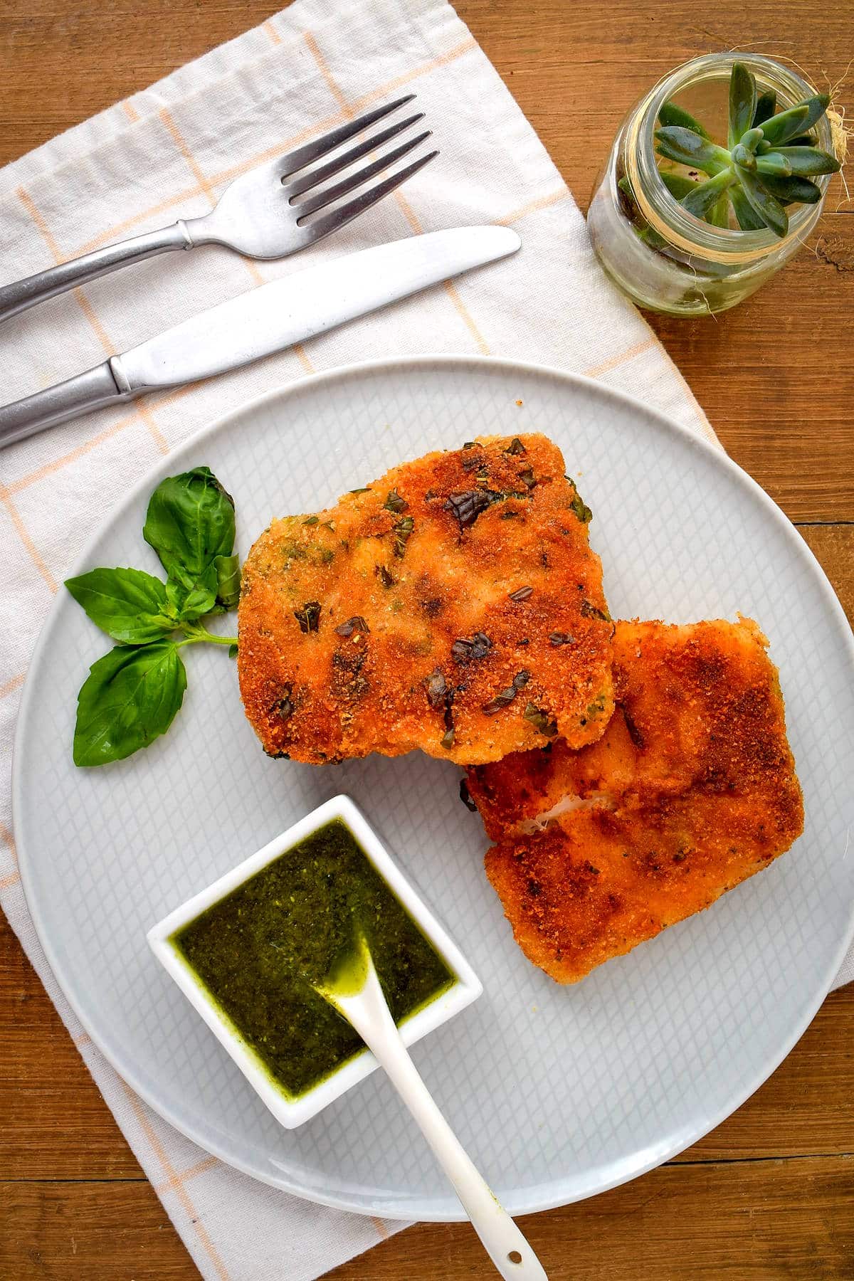 Fried fish on white, decorative plate with fresh basil.