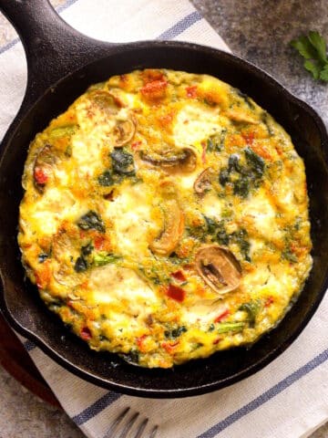 Electric skillet frittata in pan on kitchen towel.