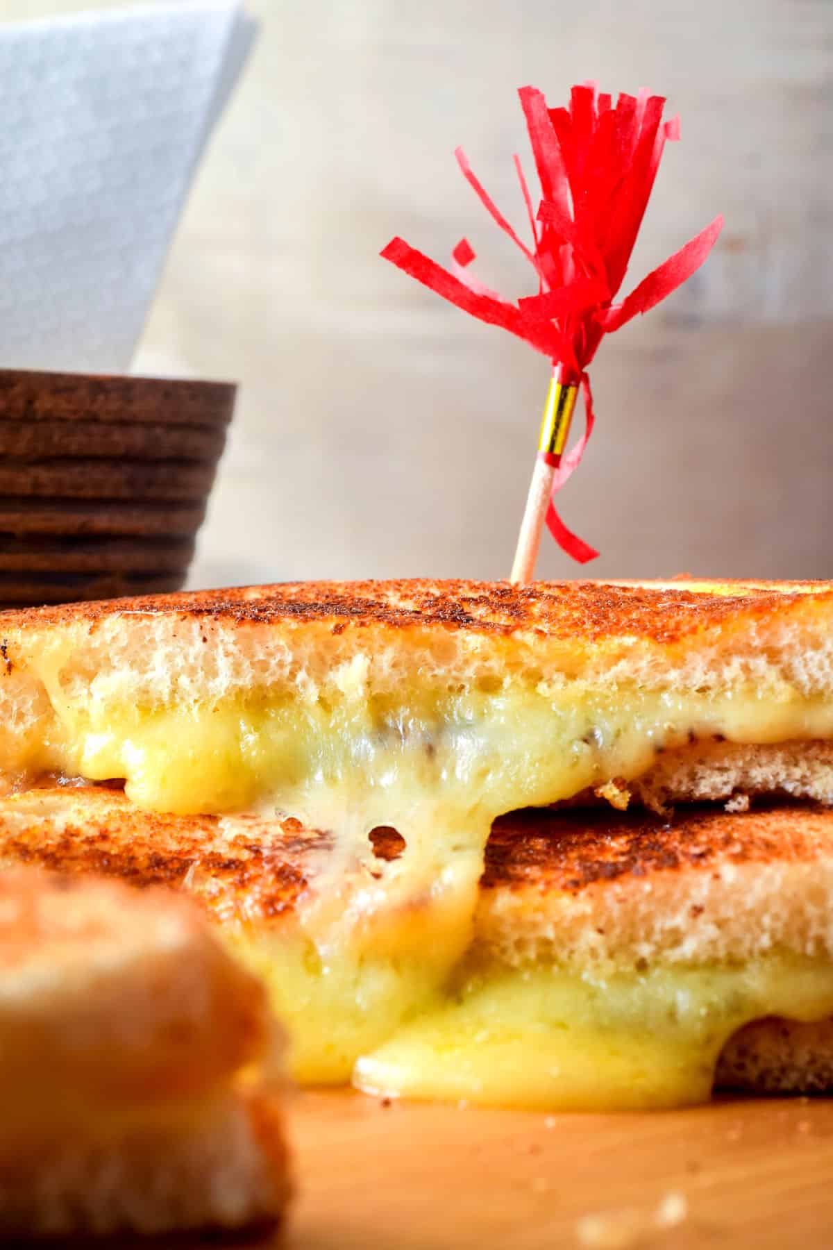 Electric skillet grilled cheese sandwiches stacked on serving board.