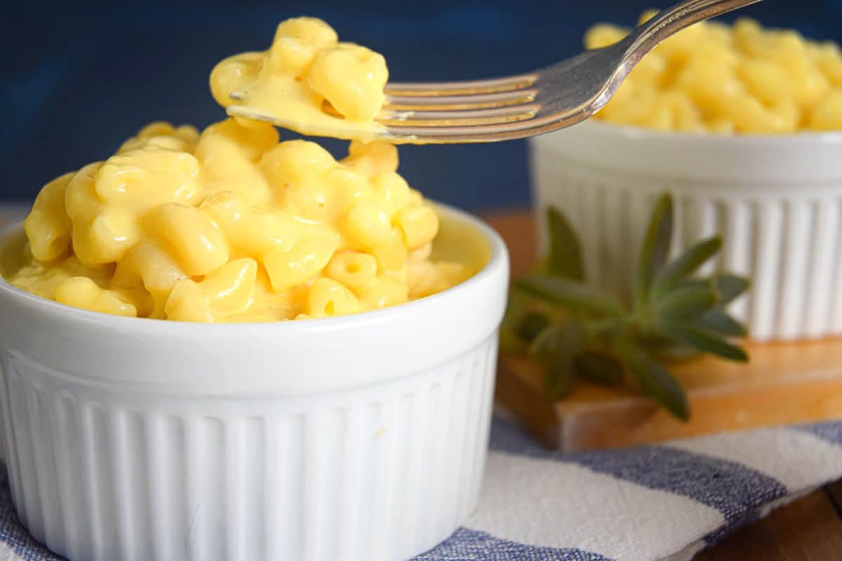 Creamy mac and cheese in white dish with a fork.