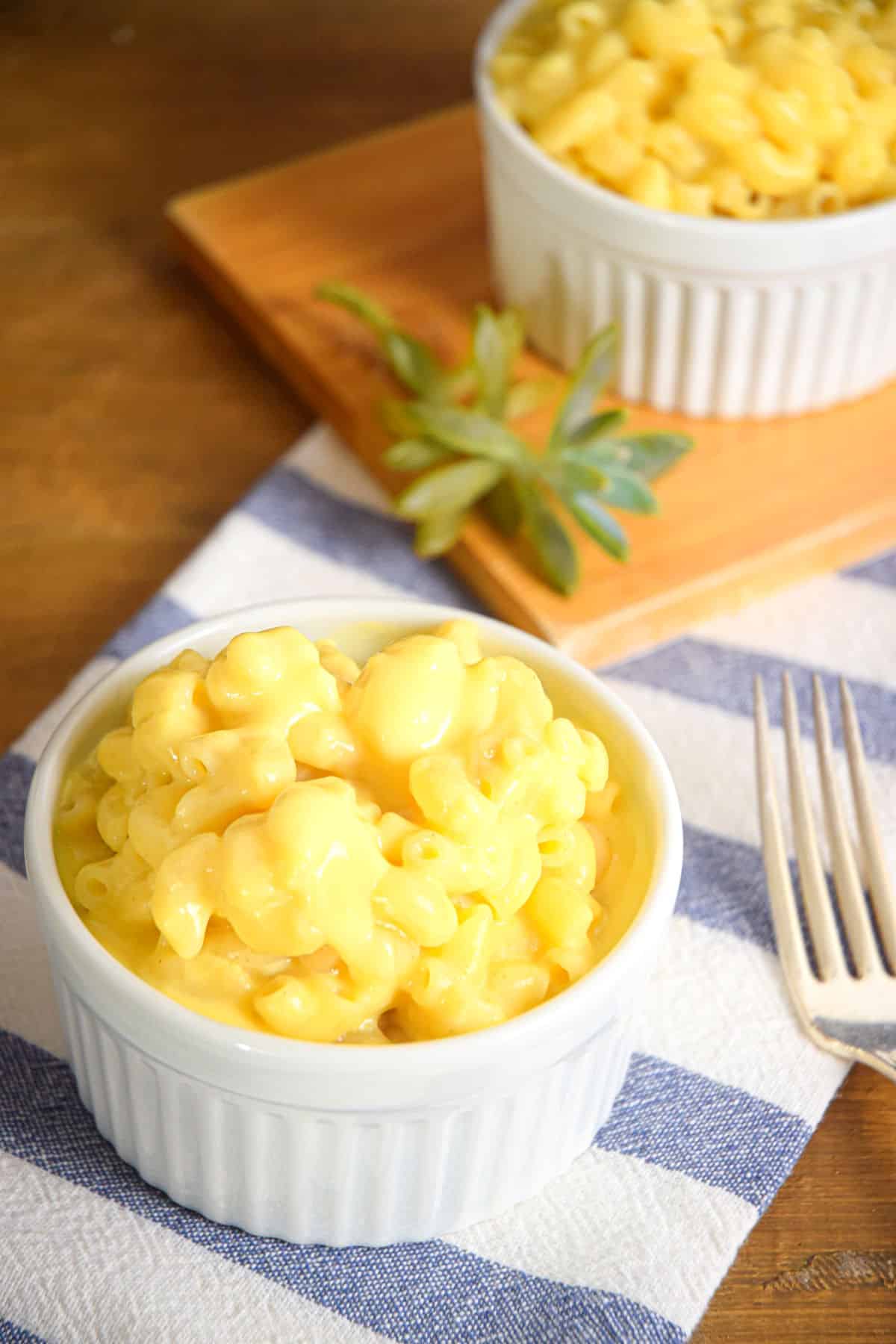 Creamy mac and cheese in white ramekins with a fork on the side.