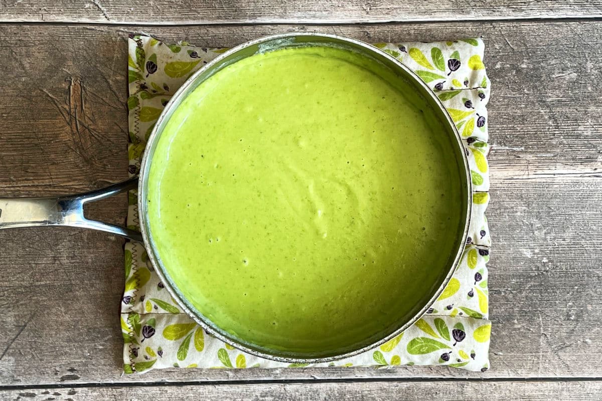 Pea puree in saucepan on wooden background.