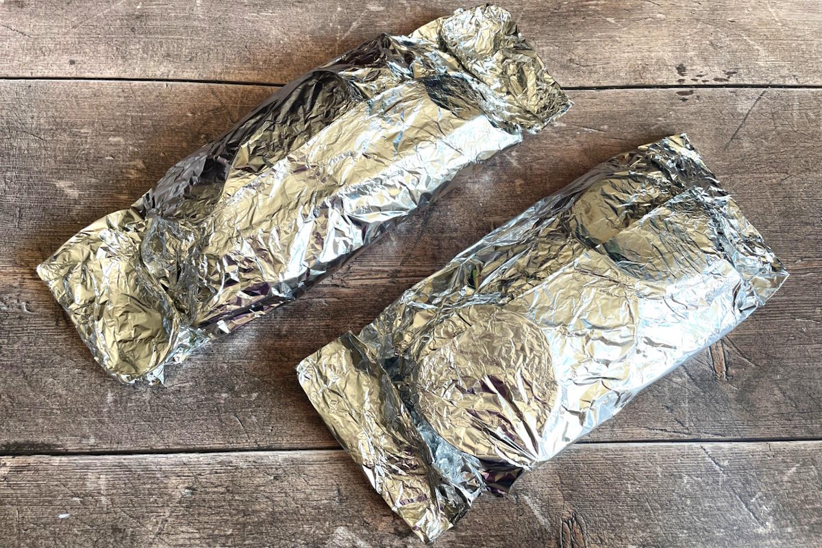 Asparagus foil packets on wooden background.