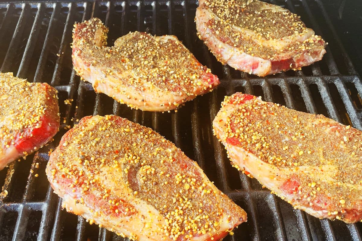 Seasoned, bison ribeye steaks on the outdoor grill.