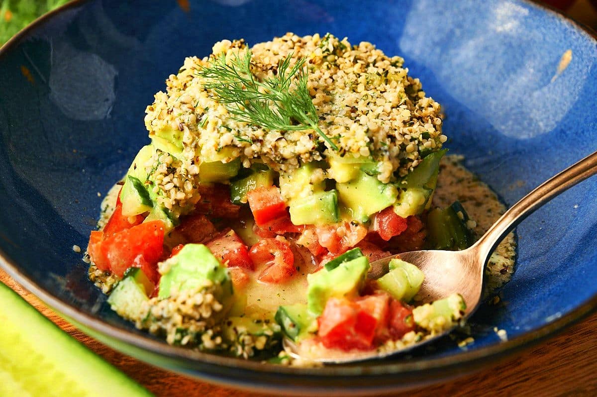 Hemp seed salad on blue plate with spoon.